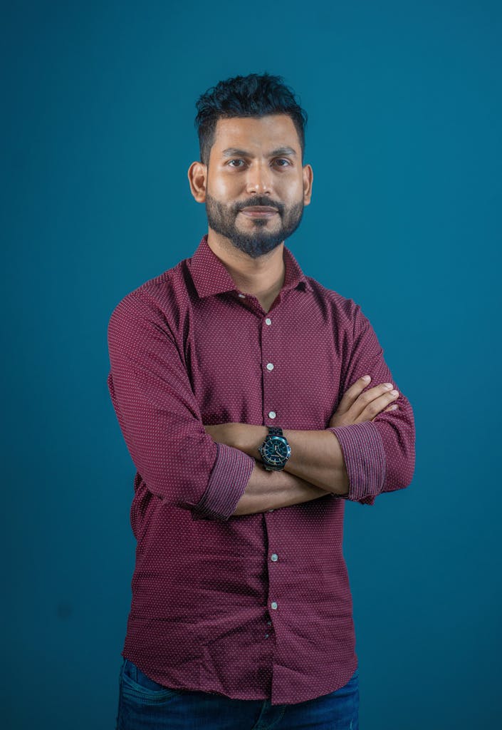 A man in a maroon shirt standing with his arms crossed